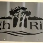 A metal sign with trees and mountains on it.