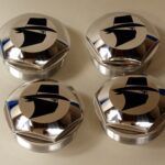 A set of four chrome caps with the logo for the company.