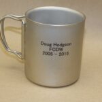 A silver mug with the name doug hodgson fcdw engraved on it.