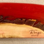 A red and brown wooden bowl with the name rouge on it.