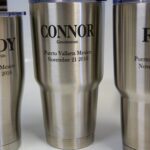 Three stainless steel cups with names and dates on them.