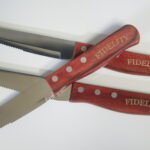 A pair of red handled scissors with the word fidelity on them.