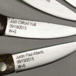 A close up of four knives with names and dates