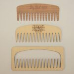 A set of four wooden combs with different designs.