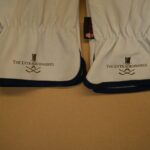A pair of white gloves with the city university logo on them.