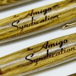 A close up of two wooden pens with the words " amigo syndication ".