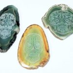 Three green agate slices with a skull on them.