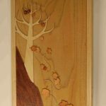 A wooden picture of a tree with leaves on it.